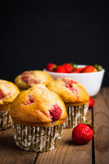 Homemade muffins with strawberries on the wooden background