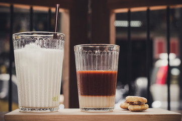 Thai Tea comes in a milk glass of cold , and syrup on a wooden t