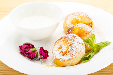 Cheesecakes on a white plate with sour cream