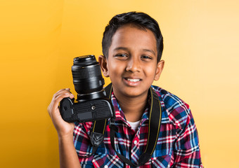 10 year old indian boy holding digital camera or DSLR camera, posing like a professional...