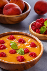 Refreshing cold peach soup garnished with raspberries and mint.