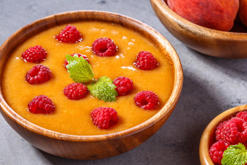 Refreshing cold peach soup garnished with raspberries and mint.