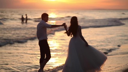 Just married couple walk hand in hand on the beach - Powered by Adobe
