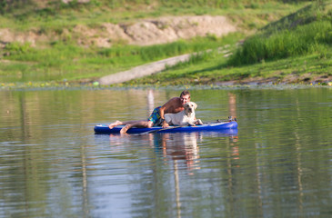 The dog and the man float by the boat on the lake.