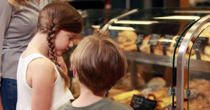 Family choosing cakes in grocery store