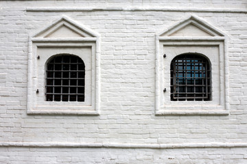 Obraz na płótnie Canvas Two windows with bars in brick wall
