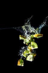 Kiwi slices falling into the water close-up, macro, splash, bubbles, isolated on black background
