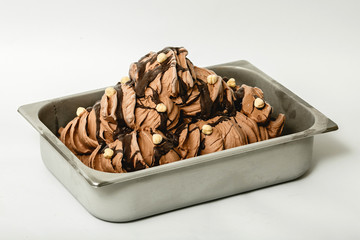 Chocolate ice cream with hazelnuts in the metal tray on white background