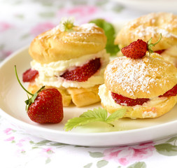 Cream puff cakes or profiterole filled with whipped cream, served with strawberries