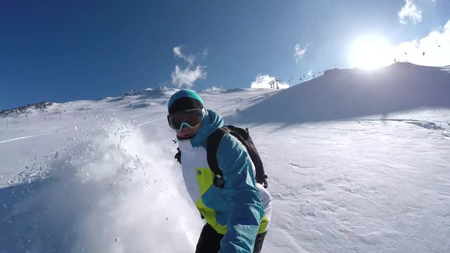 SELFIE: Snowboarder riding powder snow in mountain ski resort