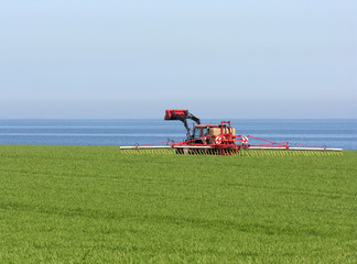 Traktor beim D&uuml;ngen eines Feldes an der Ostseek&uuml;ste bei Heiligen