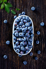 Fresh blueberries from organic cultivation in an oval ceramic pot on a wooden table