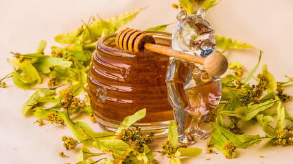 Closeup of honey dipper and lime leaves, crystal jar