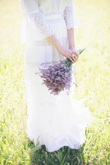 Hands of bride holding purple flower bouquet