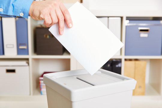 Hand mit Stimmzettel bei Wahl