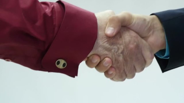 Closeup of business people shaking hands over a deal slow motion