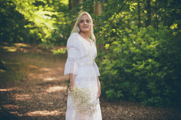 Smiling bride in white dress in forest