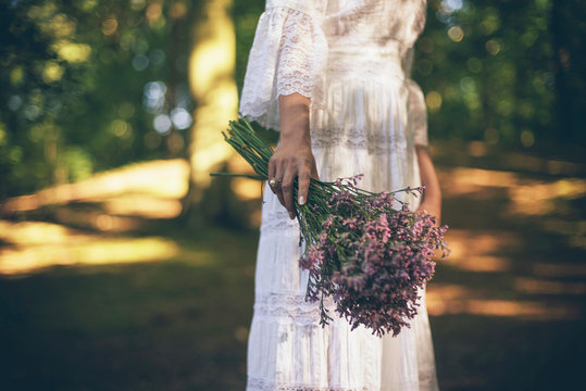 Hand of bride holding purple flowers