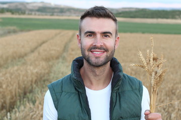 Happy smiling caucasian thirty years old farmer standing proud in front of his wheat fields