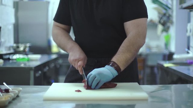 Chef prepares a meat dish in the kitchen of a restaurant