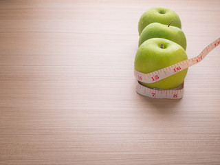 Apples with tape measure on blue wood background, lose weight concept