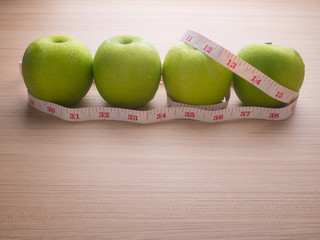 Apples with tape measure on blue wood background, lose weight concept