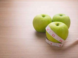 Apples with tape measure on blue wood background, lose weight concept