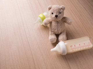 Baby bottle with milk and a measuring scale on the background of a lot of full bottles of breast milk with teddy bear and diaper. Mother's milk - the most healthy food for newborn,newborn equipment