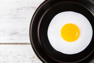 Fried egg in small pan with handle on blue wooden board