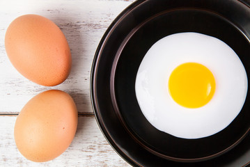 Fried egg in small pan with handle on blue wooden board