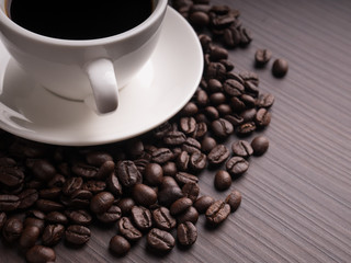 Black coffee cup on brown wood table with coffee bean