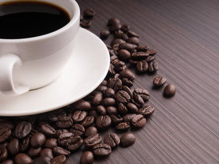 Black coffee cup on brown wood table with coffee bean