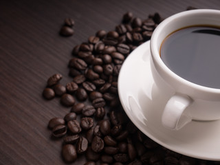 Black coffee cup on brown wood table with coffee bean