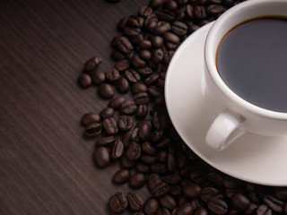 Black coffee cup on brown wood table with coffee bean
