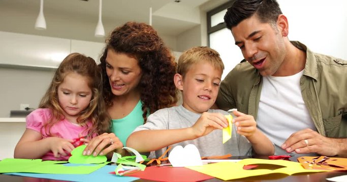 Cute parents and children doing arts and crafts at kitchen table