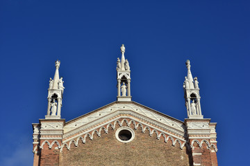 Three gothic pinnacles with saints at the top of Ss John and Paul medieval basilica in Venice