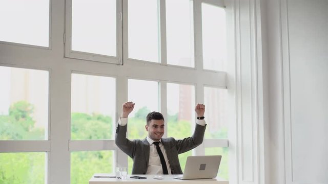 Businessman gets very good news on his computer monitor