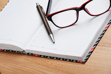 On a wooden table lie objects organizer, diary, glasses,