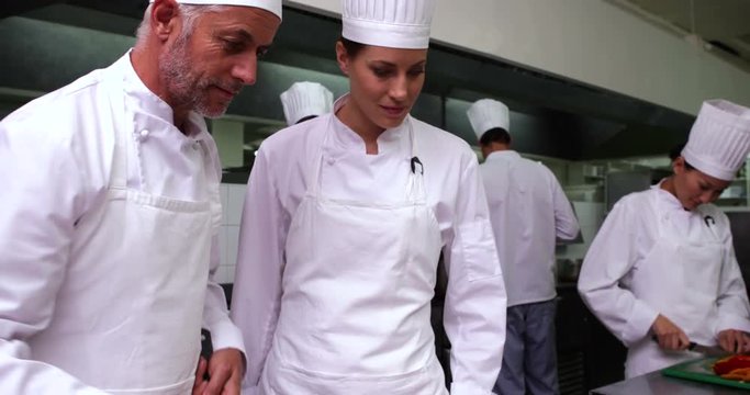 Head chef showing another how to make pizza
