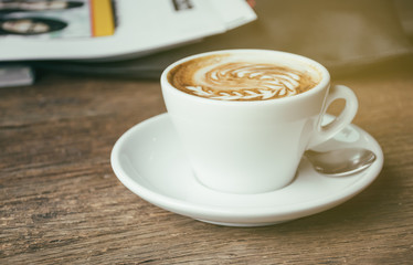 Cup of Coffee and magazine book with blur book magazine backgrou