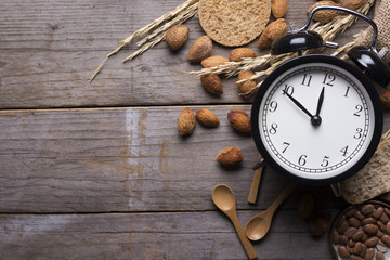Food ingredients and clock for cooking on wooden background