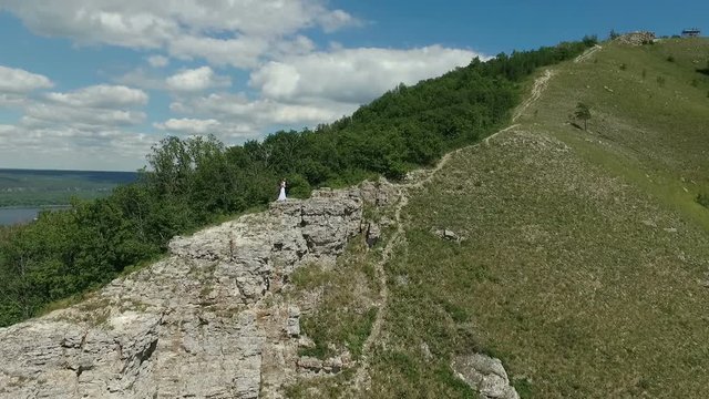 Aerial video of bride and groom standing  on the background of beautifull Mountain View. Drone flying towards them.  Full Hd stock footage clip
