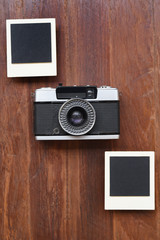 Photo frames and camera on wooden background
