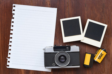 Blank paper with photo film, photo frames and camera on wooden background