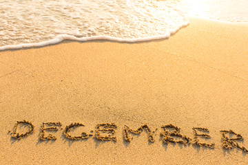 December - drawn by hand on a golden sandy sea beach.