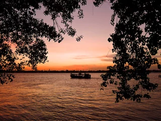 Plexiglas foto achterwand Sunset over river ganges with silhouette of trees and boat in the background © saurav005