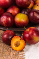 Red plums on old wooden background, selective focus