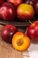 Red plums on old wooden background, selective focus