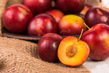 Red plums on old wooden background, selective focus