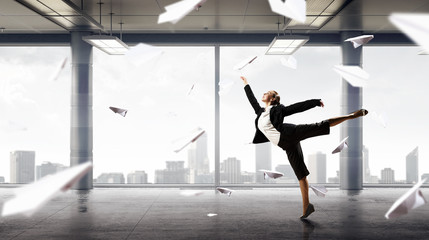 Obraz na płótnie Canvas Dancing businesswoman in office . Mixed media